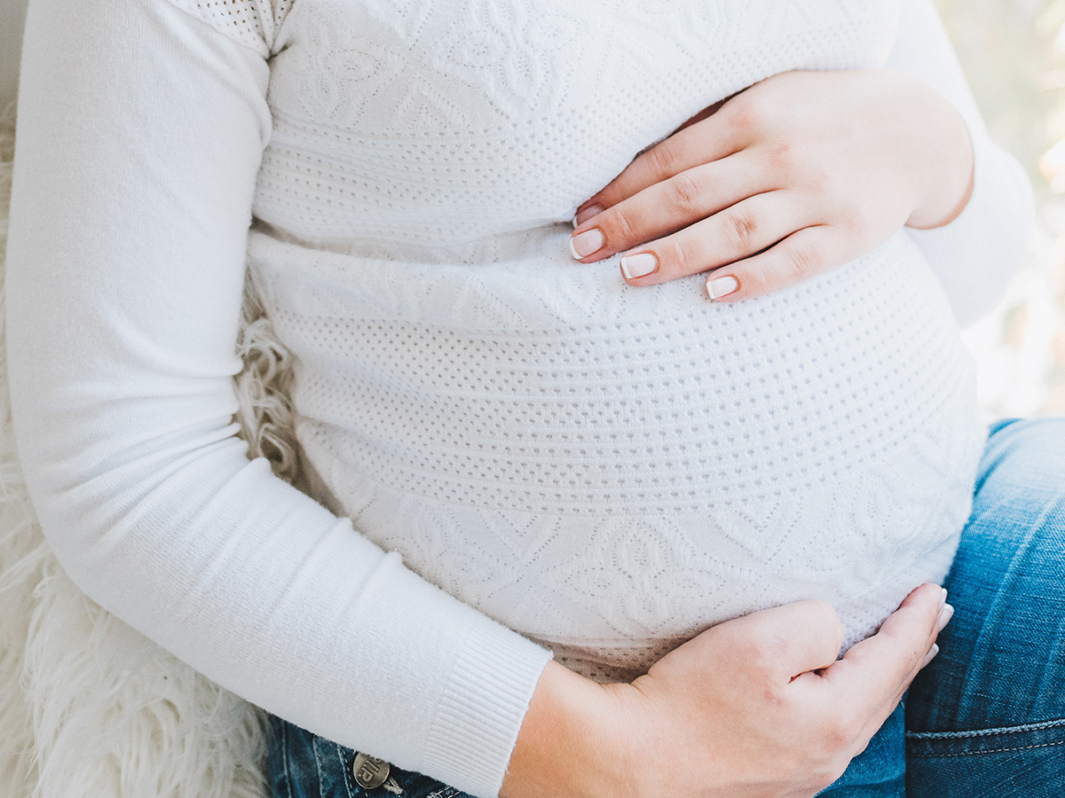 A photo of a pregnant woman cradling her stomach.