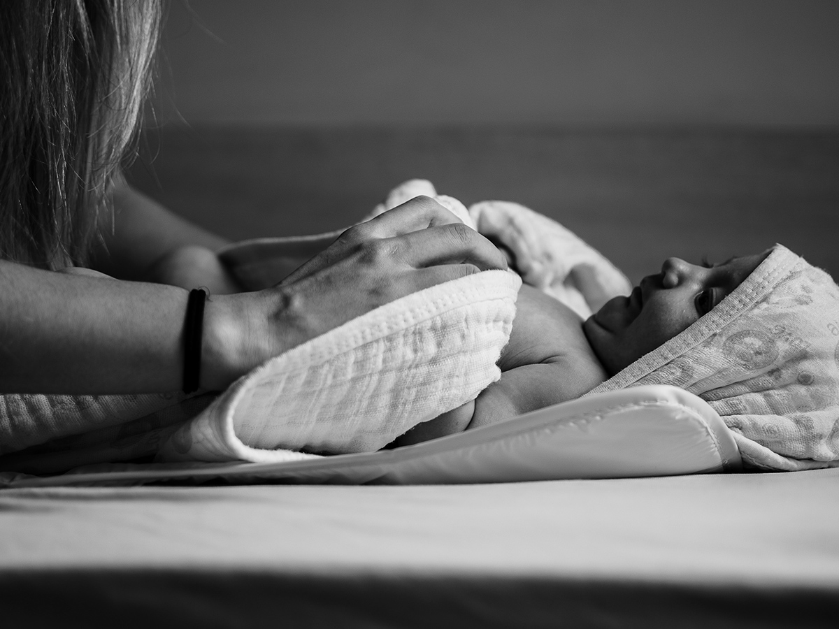 A woman swaddling a baby.